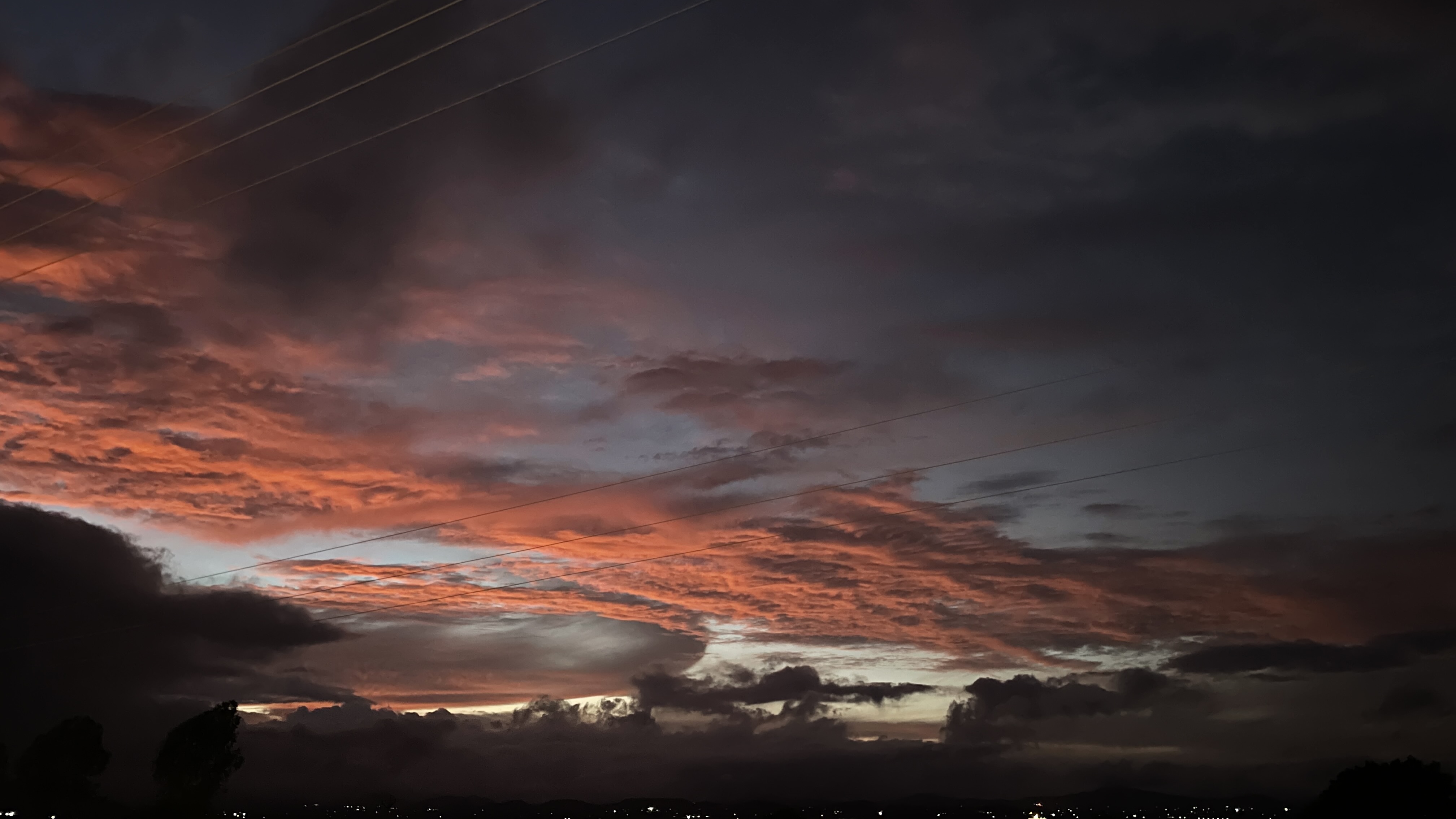 Sunset over the horizon with power lines cutting across the sky